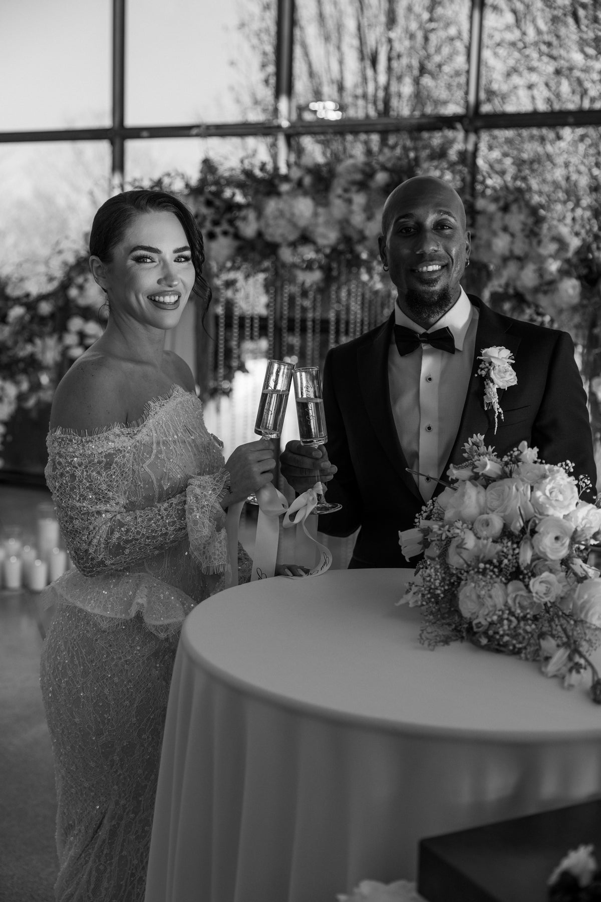 Black and white photo of a couple at a formal event with floral decorations.